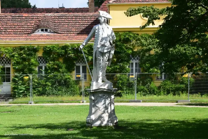 Statue Friedrichs des Großen im Park Sanssouci in Potsdam vor historischer Schlossarchitektur und Grünanlagen.